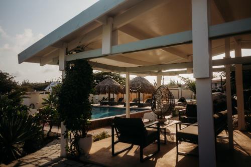 a patio with chairs and a swimming pool at Pura Vida Aruba appartement Cama in Noord