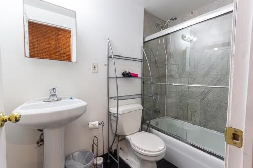 um banheiro com vaso sanitário, pia e chuveiro em Studio Plus - Cozy Apartments em Nova Iorque