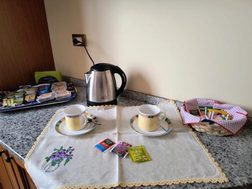 two cups and saucers on a table with a tea kettle at L'Antica Fonte di Moncioveta in Bastia Umbra