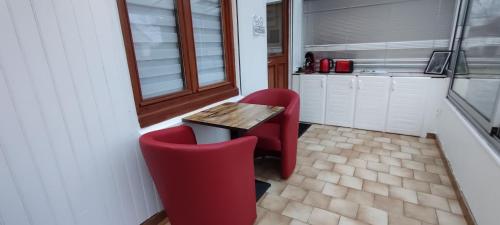une cuisine avec une table et deux chaises rouges dans l'établissement le cocon de Saeby, à Dreslincourt