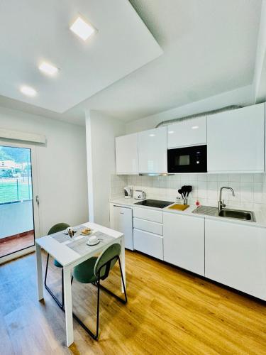a kitchen with white cabinets and a table with chairs at VALE MAR Guest in Ribeira Brava