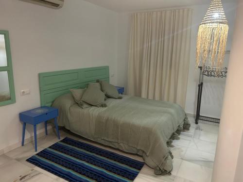 ein Schlafzimmer mit einem grünen Bett und einem blauen Stuhl in der Unterkunft Las Cumbres 1 in El Puerto de Santa María