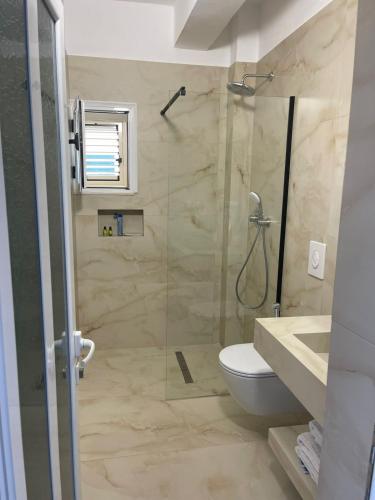 a bathroom with a shower and a toilet and a sink at Apartments Rezidenca Sinani Orikum in Orikum