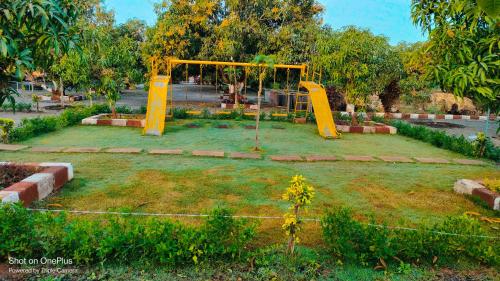 a park with a yellow swing set in the grass at AamraKunj Gir Resort in Sasan Gir