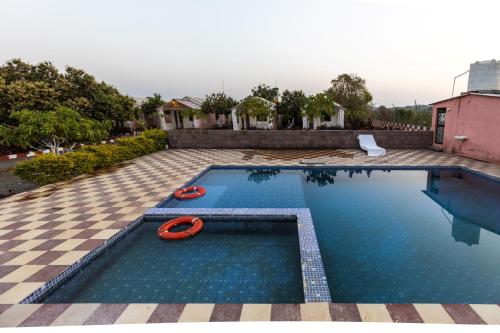 a swimming pool with two red paddles in the water at AamraKunj Gir Resort in Sasan Gir