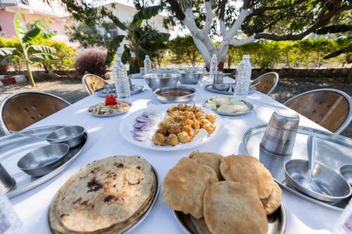 a white table with plates of food on it at AamraKunj Gir Resort in Sasan Gir