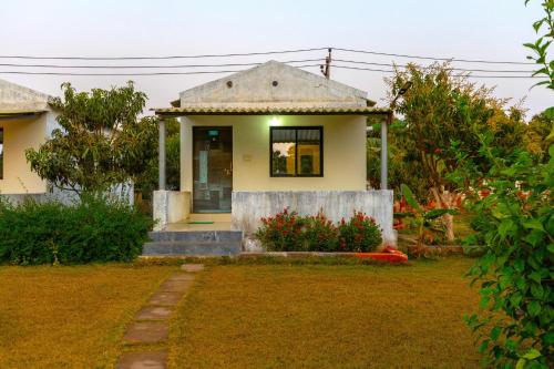 a small yellow house with a window and a yard at AamraKunj Gir Resort in Sasan Gir