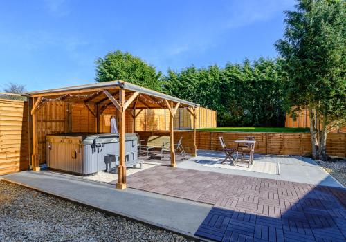 a barbecue under a wooden gazebo in a backyard at Oxendon Oasis- Luxury Hot Tub Retreat in Market Harborough