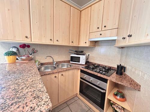 a kitchen with wooden cabinets and a sink and a microwave at Apartamento La Plaza! in Bogarra