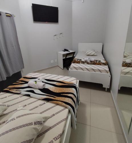two beds in a room with a tv on the wall at Hotel Amanhecer n903- feirinha da madrugada-Brás in Sao Paulo