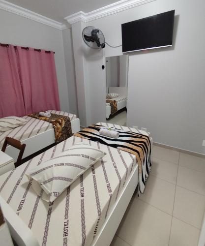 two beds in a room with a flat screen tv at Hotel Amanhecer n903- feirinha da madrugada-Brás in Sao Paulo