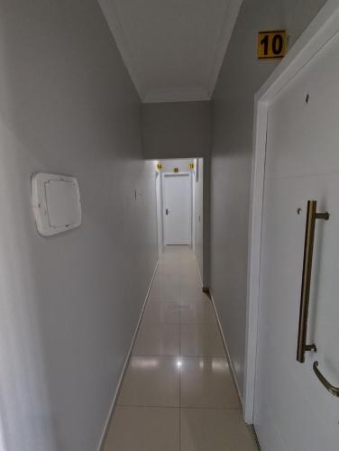 a long hallway with a white wall and a white door at Hotel Amanhecer n903- feirinha da madrugada-Brás in Sao Paulo