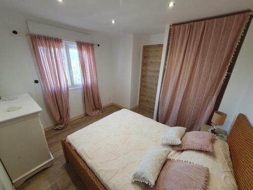 une chambre avec un grand lit avec des rideaux roses dans l'établissement appartement paisible neuf, à Hyères