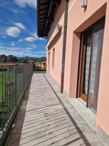 a wooden walkway next to a pink building at Casa Vacanze La Favola Rosa sul Lago di Varese in Gavirate