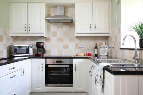 a kitchen with white cabinets and a black oven at Greenfinch in Lucker