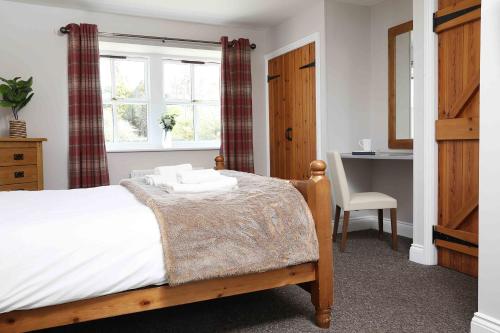 a bedroom with a bed and a desk and a window at Greenfinch in Lucker