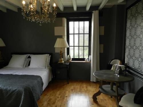 a bedroom with a bed and a table and a chandelier at Moulin de la Chevriere in Saché