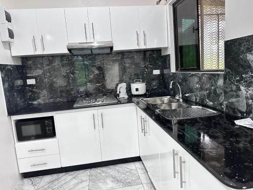 a kitchen with white cabinets and a sink at Airport Dock Apartments in Nadi