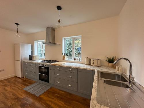 a kitchen with a sink and a stove at Cosy Bungalow Retreat in Grays Thurrock