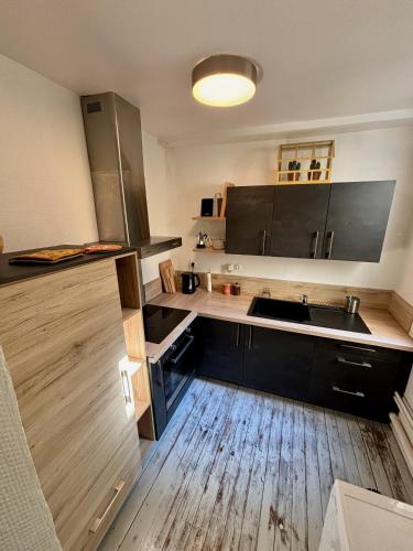 une cuisine avec des armoires noires et un plancher en bois dans l'établissement Cosy getaway in historic Bayeux, à Bayeux