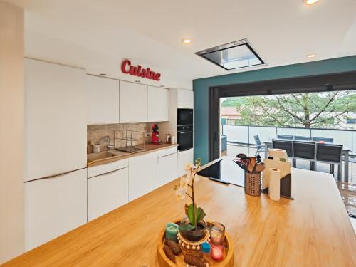 a kitchen with white cabinets and a wooden table at Appartement terrasse neuf et cosy au calme in Lattes
