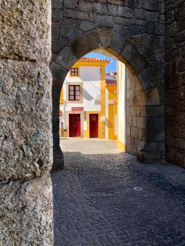 an archway in a stone wall with a building at A Casinha do Arco, Porta da Vila in Nisa