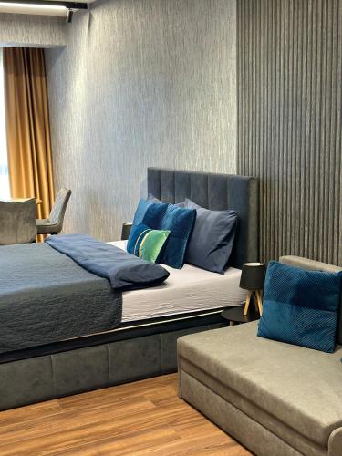 a bedroom with two beds with blue pillows and a couch at West Point Luxury studio in Plovdiv