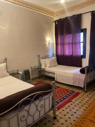 a bedroom with two beds and a window with purple curtains at dar hassbia in Fez