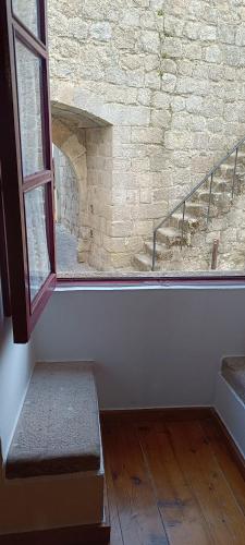 an empty room with a window and a staircase at A Casinha do Arco, Porta da Vila in Nisa