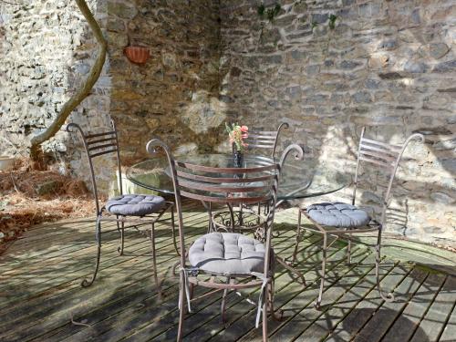 a table with four chairs and a table with a stone wall at Le Mosaïque, proche gare, terrasse, parking privé in Laval