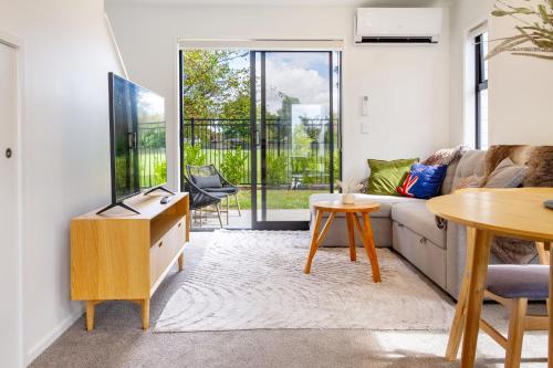 a living room with a couch and a tv and a table at Escape at the park: 1 bed 1 bath w/carpark in Christchurch
