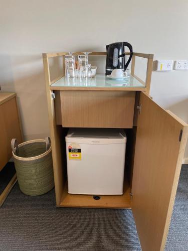 a small cabinet with a shelf and a refrigerator at Deluxe studio at Mantra in Darwin