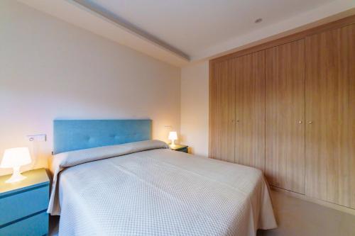 a bedroom with a bed with a blue headboard and cabinets at ASTURES Viviendas Turísticas in Oviedo