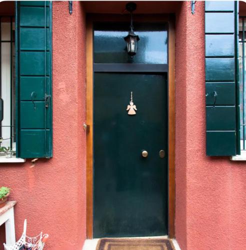 a green door on a red building with green shutters at Dorsoduro House in Venice
