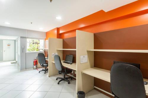 an office with desks and chairs and an orange wall at Lapa Loft, estúdio vintage com total infraestrutura na Lapa, RJ in Rio de Janeiro