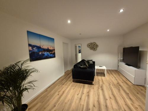 a living room with a black couch and a flat screen tv at Kezara Living in Konz