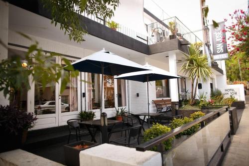 eine Außenterrasse mit Tischen und Stühlen und einem Sonnenschirm in der Unterkunft Hotel San José in Villa Carlos Paz