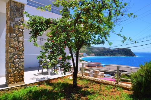 a tree in front of a building with a view of the ocean at Harmonia Himara in Himare