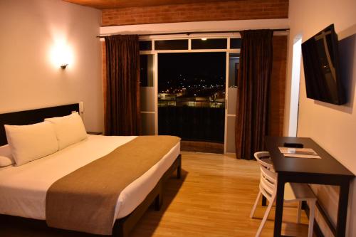 a hotel room with a bed and a desk and a window at Hotel San Marcos in Paipa