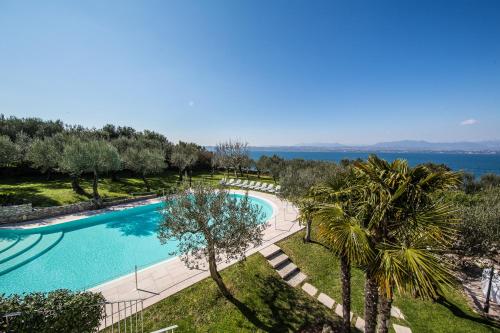 an overhead view of a swimming pool with trees and water at Appartamento Ideal in Sirmione