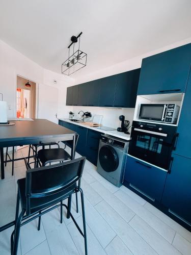 une cuisine avec des placards bleus, une table et un four micro-ondes dans l'établissement Le Terra Rosa, à Plaisance-du-Touch