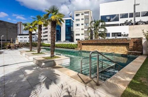 een zwembad met palmbomen en gebouwen bij Define Pinheiros 34 in Sao Paulo