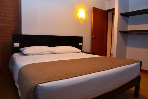 a bedroom with a large bed with white sheets and pillows at Hotel San Marcos in Paipa