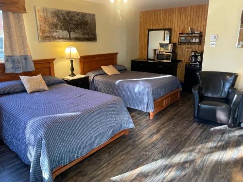 a hotel room with two beds and a chair at Auberge et Chalets sur le Lac in Lac-Mégantic
