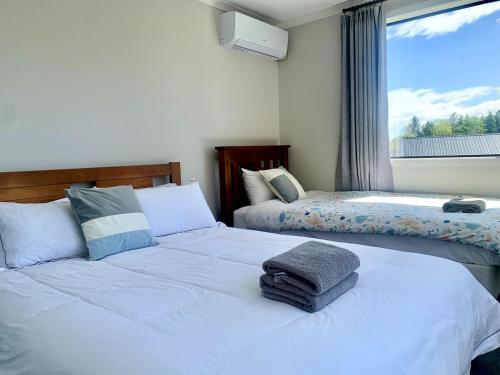 a bedroom with two beds and a window at Lifestyle with Tennis Court in Tamahere