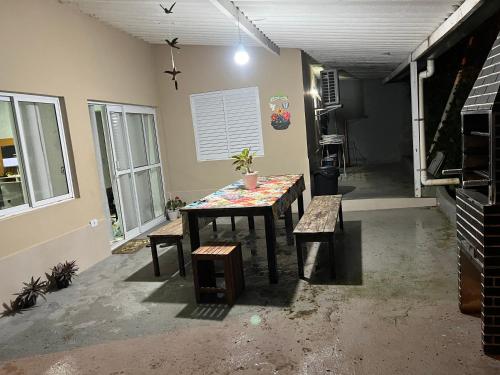 una habitación con una mesa y bancos en una habitación en Casa aconchegante em Ubatuba, en Ubatuba