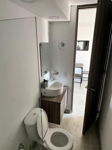 a bathroom with a toilet and a sink and a mirror at Coco Loft Apartamento cerca del Malecón del Río in Barranquilla