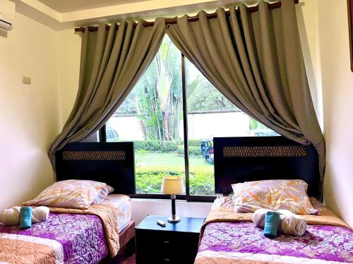 two beds in a bedroom with a window at Jaco Hideaway Oasis in Jacó