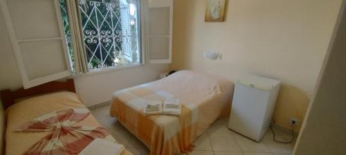 a small bedroom with two beds and a window at Suítes Casa Branca in Guarujá