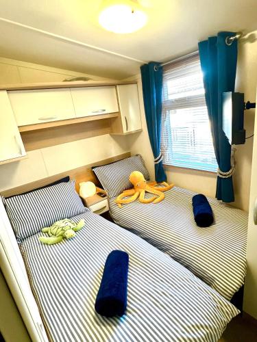 two twin beds in a small room with blue curtains at The Puffins Rest in Tenby